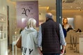 A middle aged couple looking in a shop window at goods for sale