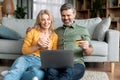 Middle Aged Couple Making Online Shopping While Relaxing With Laptop At Home Royalty Free Stock Photo