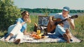 A middle-aged couple, a man and a woman, play the guitar and talk cheerfully at a picnic on a sunny summer day Royalty Free Stock Photo