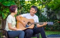 Middle aged couple playing guitar while relax sitting on bench