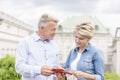 Middle-aged couple reading guidebook outside building