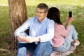 Middle aged couple sitting back to back and using smartphones outdoors Royalty Free Stock Photo