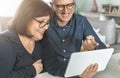 Middle aged couple smiling while shopping online - seniors chat with friends and family - warm filter on background