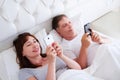 Middle aged couple using mobile telephones in bedroom, happy people Royalty Free Stock Photo