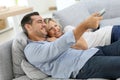 Middle-aged couple watching tv on sofa