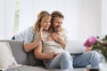 Middle-aged couple wearing casual clothes and sitting at home on the sofa and using a laptop Royalty Free Stock Photo