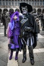 Middle aged couple - woman in purple carnival suit, man in Puss in Boots suit - at carnival in Venice, Italy