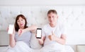 Middle aged couple - woman hold phone and showing sign of dislike, man hold mobile phone and show like, blank screen Royalty Free Stock Photo