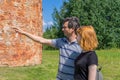 Middle aged dark-haired tourist man showing direction by hand for young redhead lady. Traveler asking path from stranger on