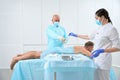 Middle-aged doctor operates on a man in sterile operating room Royalty Free Stock Photo