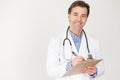 Middle aged doctor with a stethoscope around his neck and holding a file of patients records in his hands taking some notes