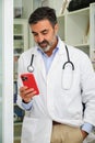 Middle aged doctor using his smartphone in his break. Royalty Free Stock Photo