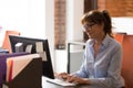 Middle aged employee typing using keyboard looking at computer screen