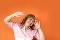 Middle-aged European woman is standing, protestingly extending both hands, on an orange background