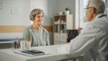 Middle Aged Family Doctor is Talking with Senior Female Patient During Consultation in a Health Royalty Free Stock Photo