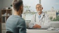 Middle Aged Family Doctor is Talking with Young Male Patient During Consultation in a Health Clinic Royalty Free Stock Photo