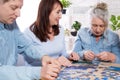 Middle-aged family elderly collects jigsaw puzzles at the table in the room