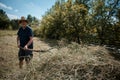 Middle-aged farmer making a haystack with a pitchfork for the winter on a sunny day in autumn. Agricultural work. Hay harvesting Royalty Free Stock Photo