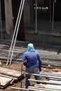 Middle aged fat woman working as a laborer stacking scaffolding pipe at building work site, a job fit for a man.