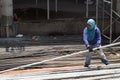 Middle aged fat woman working as a laborer stacking scaffolding pipe at building work site, a job fit for a man.