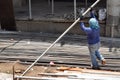 Middle aged fat woman working as a laborer stacking scaffolding pipe at building work site, a job fit for a man.