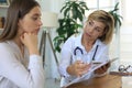 Middle aged female doctor therapist in consultation with patient in office