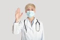 Middle aged female doctor in white coat with stethoscope in protective mask, shows stop sign with hand Royalty Free Stock Photo