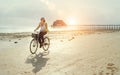 Middle-aged female dressed light summer clothes riding old vintage bicycle with front basket on the lonely low tide ocean white Royalty Free Stock Photo