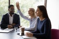 Middle-aged female employee raise hand at office meeting