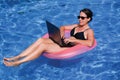 Middle aged female executive workaholic working on laptop computer in swimming pool on vacation Royalty Free Stock Photo