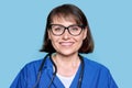 Middle aged female nurse in blue uniform with stethoscope smiling looking at camera Royalty Free Stock Photo