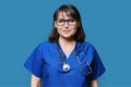Middle aged female nurse in blue uniform with stethoscope smiling looking at camera Royalty Free Stock Photo