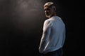 Middle-aged good looking man in white t-shirt posing in front of a black background with copy space.