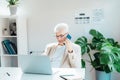 Middle aged gray hair businessman talking on mobile phone and using laptop while working at home office. Confident Royalty Free Stock Photo