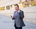 Middle aged handsome businessman using mobile phone app sending message outside office in urban city Royalty Free Stock Photo