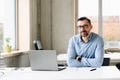 Middle aged handsome man in shirt working on laptop computer in office