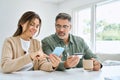 Middle aged happy couple using smartphone holding credit card buying online. Royalty Free Stock Photo
