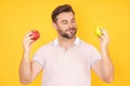 Middle aged happy smiling man bitting apple, healthy lifestyle. Man holds a fresh green apple studio portrait on yellow
