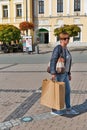 Middle aged happy woman with shopping bags walking on street.