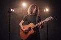 Talanted hispanic musician playing guitar in stage lights