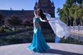 Middle-aged Hispanic woman in turquoise dress with rhinestones, belly dancing with a white veil. Belly dance concept Royalty Free Stock Photo