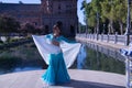 Middle-aged Hispanic woman in turquoise dress with rhinestones, belly dancing with a white veil. Belly dance concept Royalty Free Stock Photo