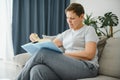 Middle-aged housewife sitting on sofa with book, free time retirement, hobby. Royalty Free Stock Photo