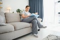 Middle-aged housewife sitting on sofa with book, free time retirement, hobby. Royalty Free Stock Photo