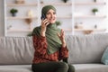 Middle-Aged Islamic Female Speaking By Phone Sitting At Home