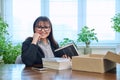 Middle-aged joyful woman with new books unpacked from cardboard box Royalty Free Stock Photo