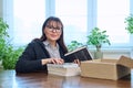 Middle-aged joyful woman with new books unpacked from cardboard box Royalty Free Stock Photo