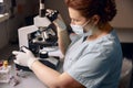 Middle aged lab technician adjusts microscope to research material sample at workplace Royalty Free Stock Photo