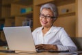 Corporate portrait of attractive and happy successful mature Asian woman working at laptop computer desk smiling confident and Royalty Free Stock Photo