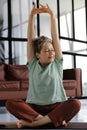 A middle aged lady practices yoga at home. A woman with closed eyes in bliss sits on a mat on the floor in the lotus